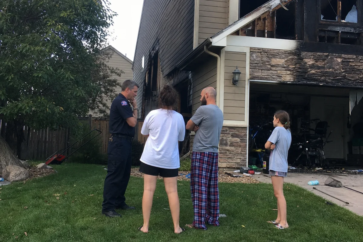 Family outside a fire damaged home with first responder